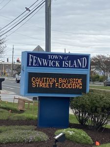 Town sign urging caution of street flooding on bayside